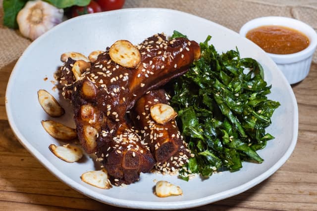 Costelinhas suínas glaceadas com molho à base de cerveja artesanal acompanhadas de couve crocante